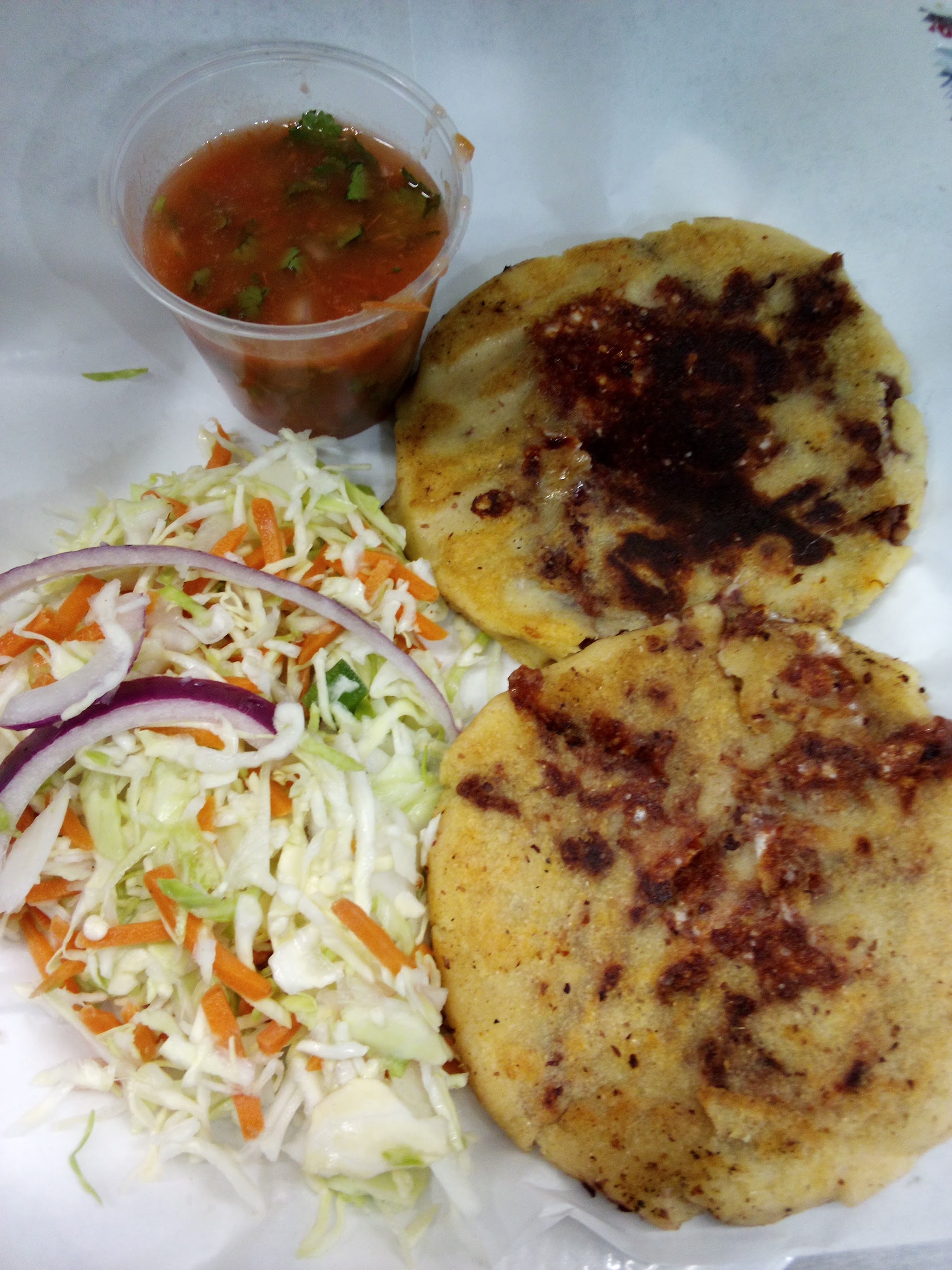 Two sopes served with slaw and a cup of red salsa