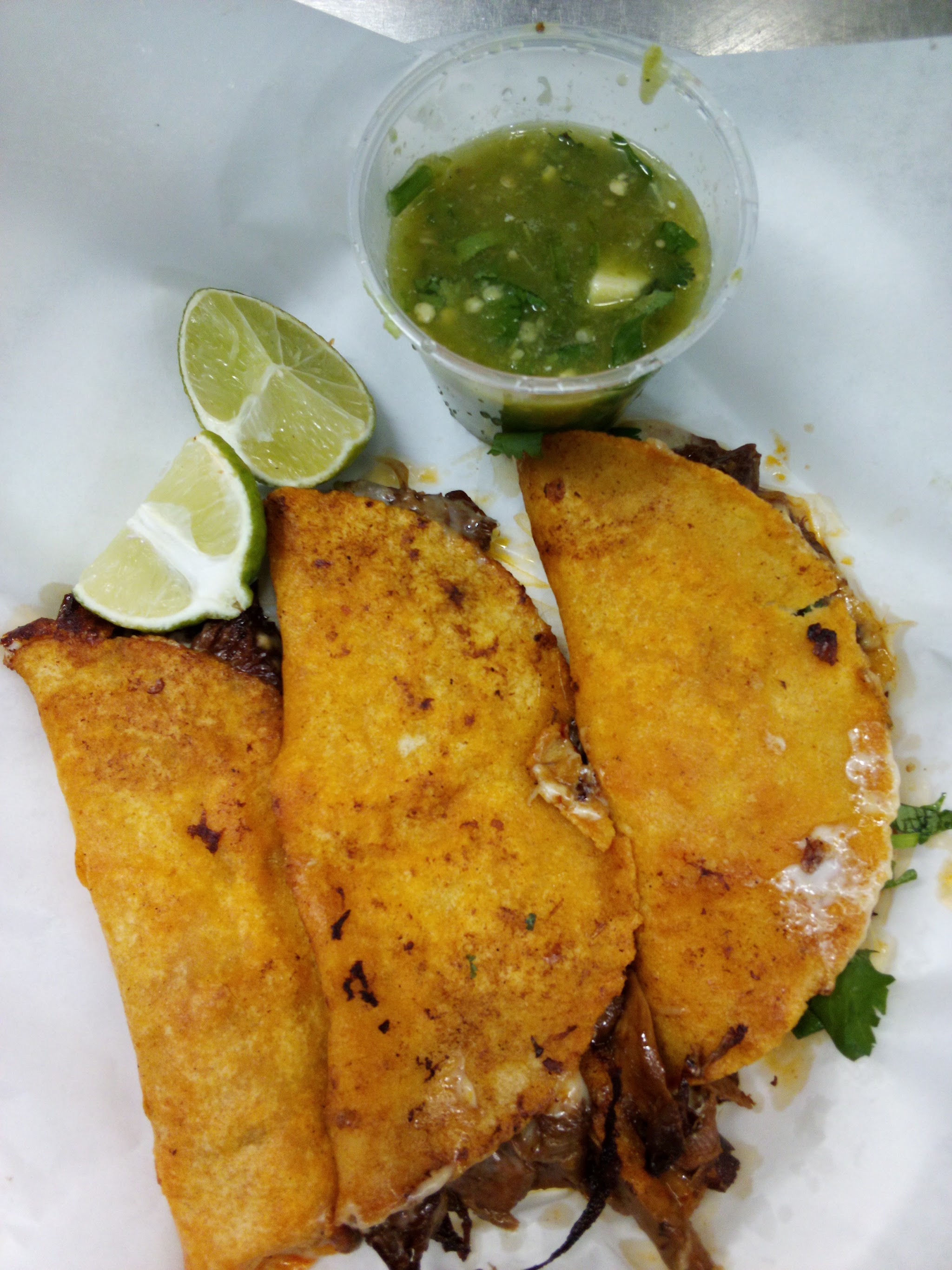 Three crispy cheese-crusted tacos with salsa verde and lime